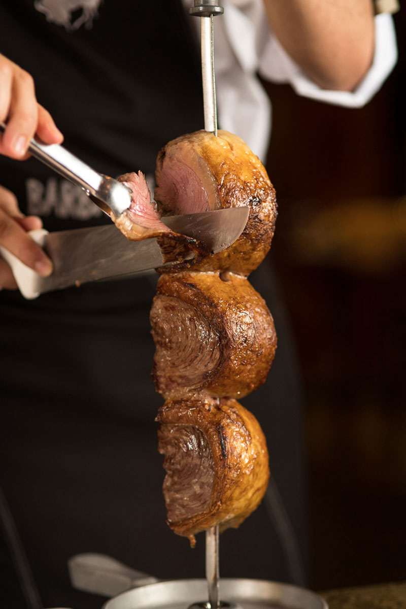 Picanha ao ponto sendo cortada no espeto