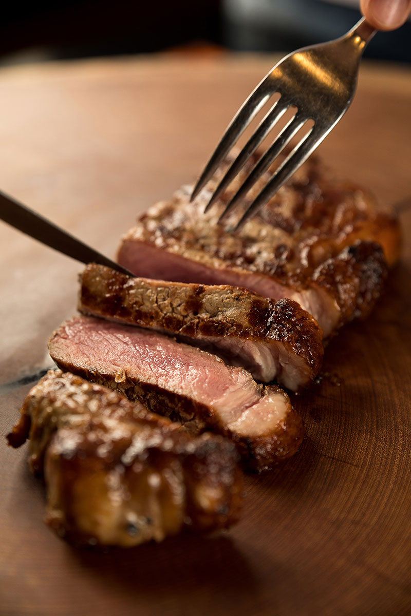 Uma bonita peça de contra filet sendo fatiada na tábua de madeira